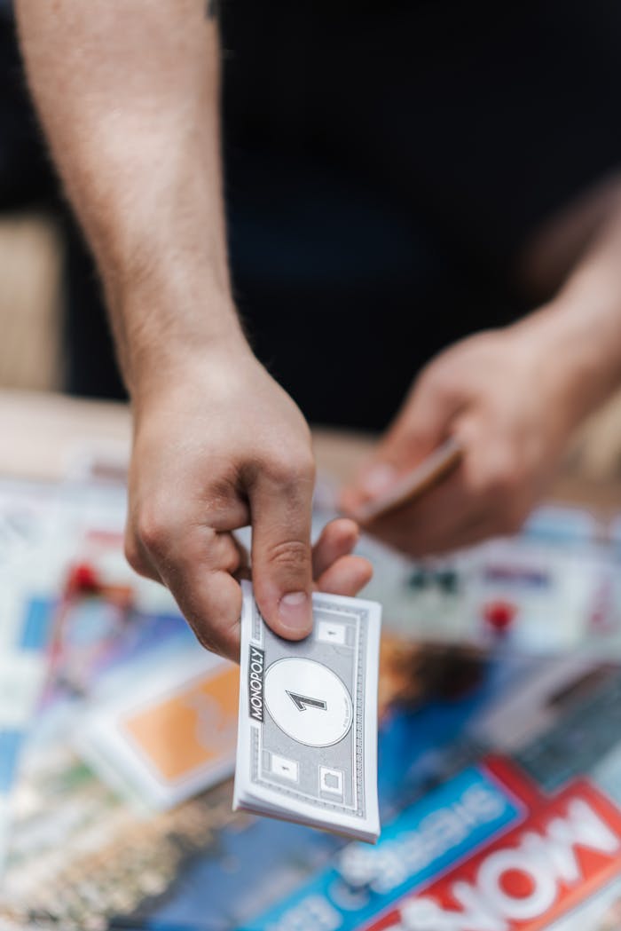 Detailed close-up of a hand exchanging Monopoly money over the board game setup.